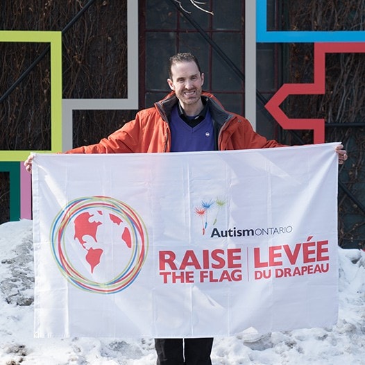 David Moloney holding an Autism Ontario flag