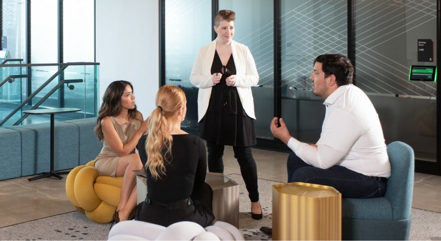 Four CIBC employees talking in an open workspace with comfortable seating.