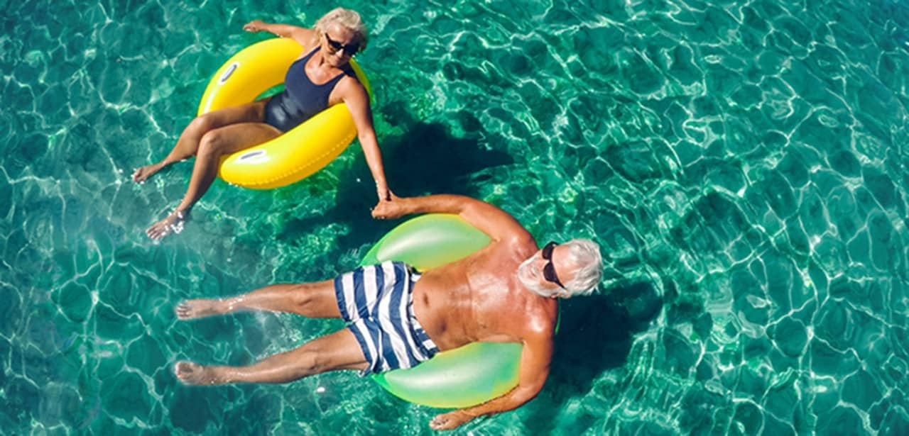 Un couple d’âge mûr se relaxe sur des bouées gonflables à la piscine