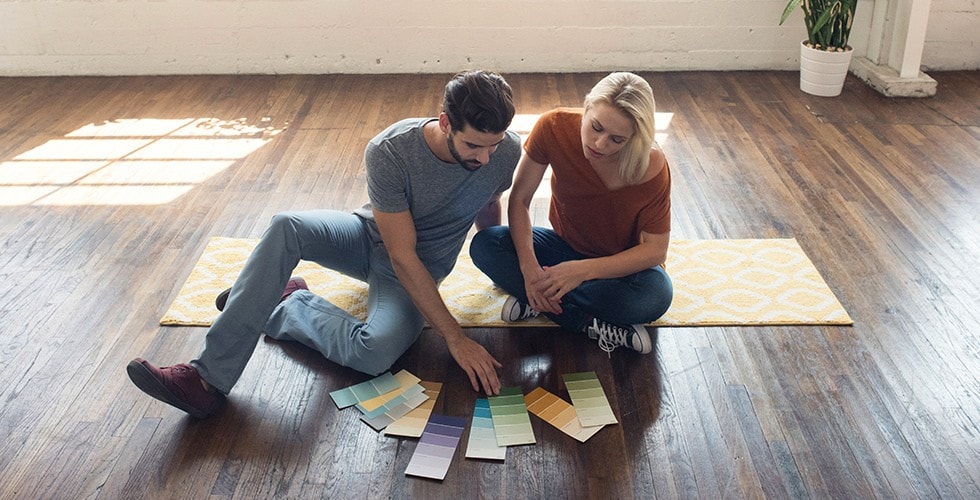 Couple sitting on the floor looking at paint samples